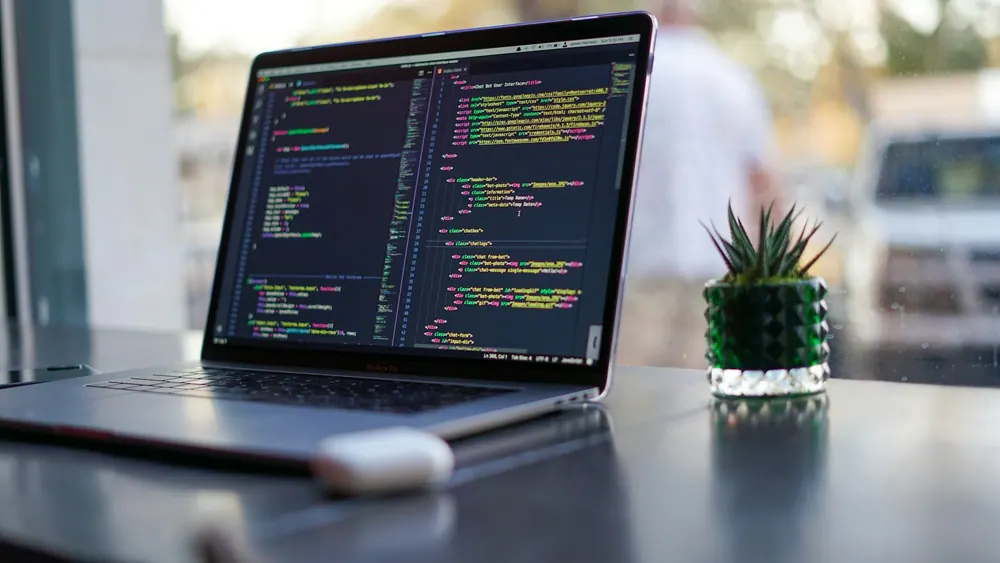 Laptop showing source code on a desk