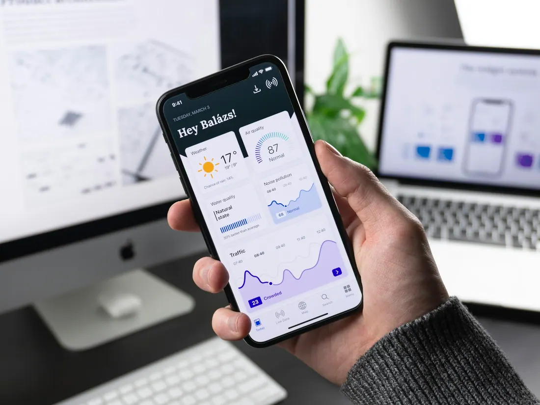 Hand holding a phone with a mobile app dashboard